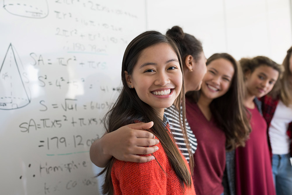 Group of multi racial students smiling at the camera during a Math Class.